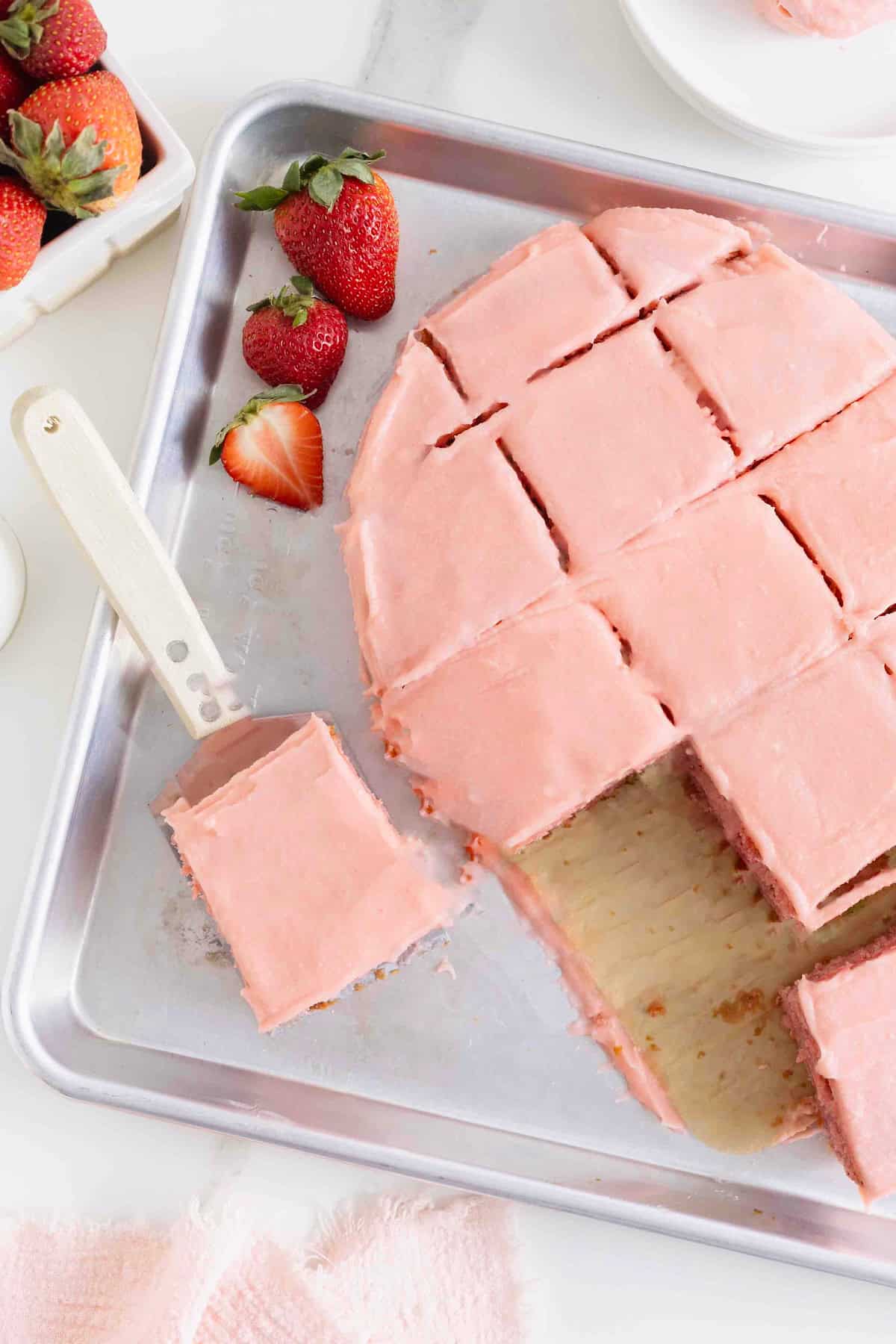 A pink frosted heart shaped cake cut into squares.