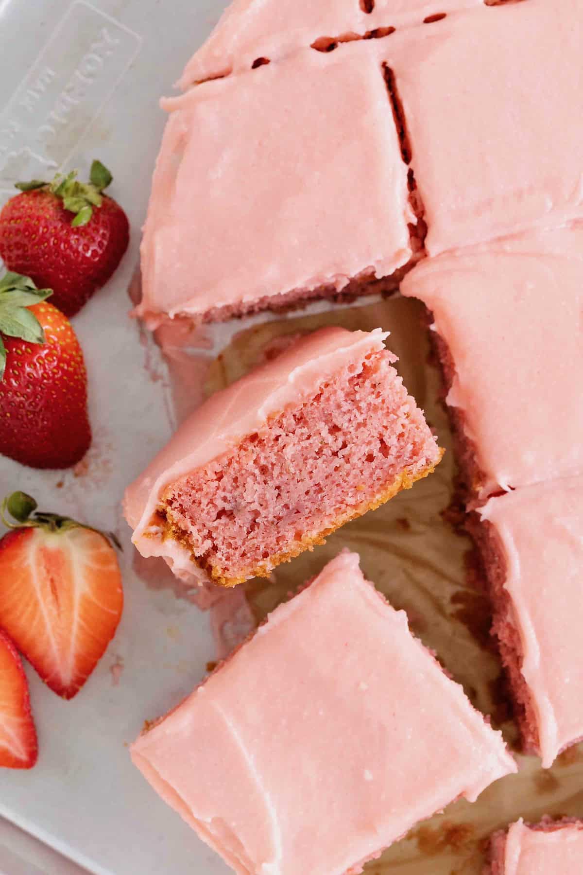 A slice of strawberry cake turned sideways next to the heart shaped cake.