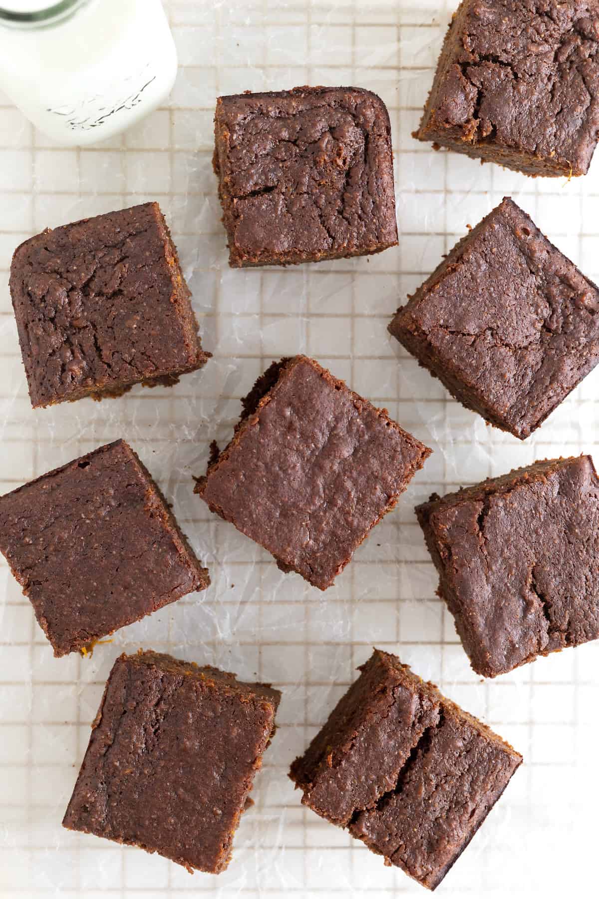 Seven whole wheat sweet potato brownies on a parchment lined gold toned cooling rack.