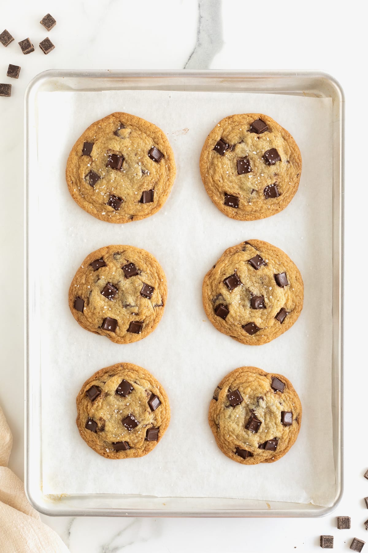 Baked chocolate chunk cookies on a parchment lined baking sheet.