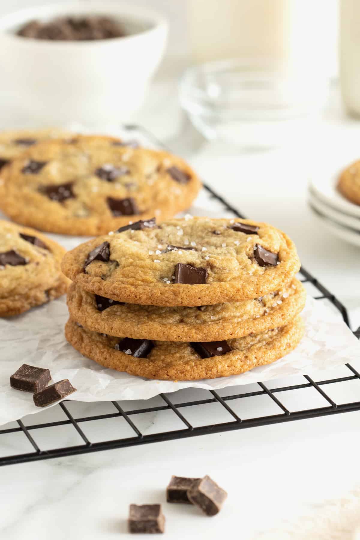 Three chocolate chunk cookies in a stack on a parchment lined cooling rack. 