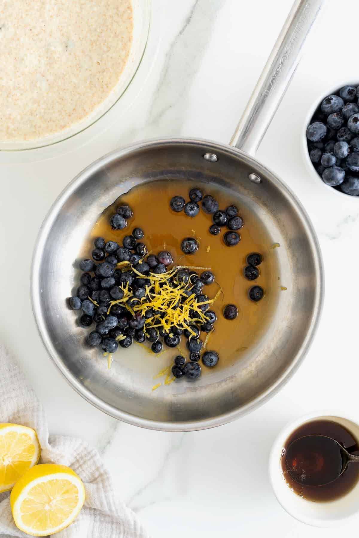 Ingredients to make blueberry lemon syrup in a sauce pan.