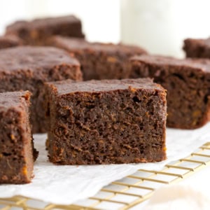 Seven whole wheat sweet potato brownies on a parchment lined gold toned cooling rack.