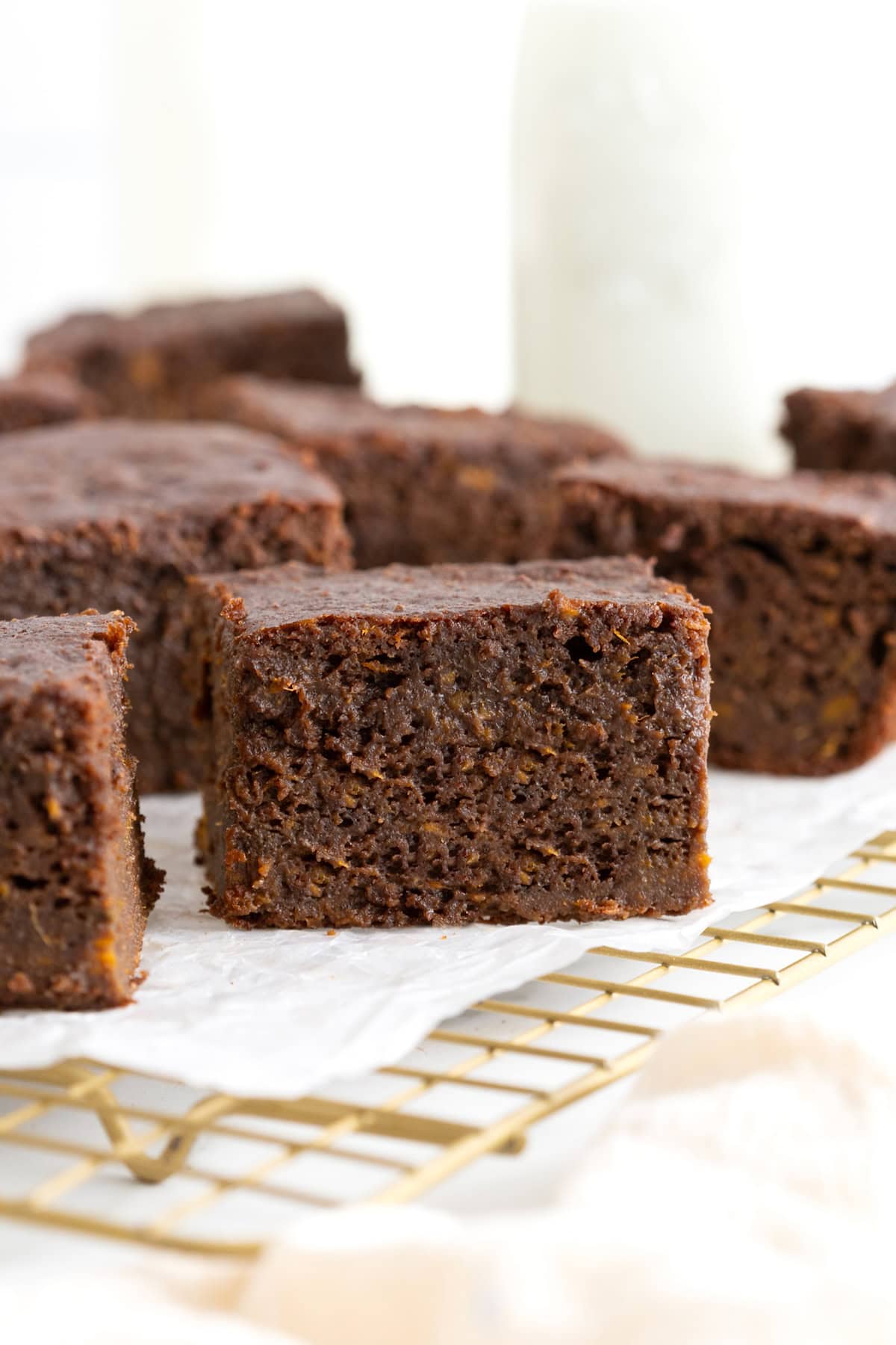 Seven whole wheat sweet potato brownies on a parchment lined gold toned cooling rack.
