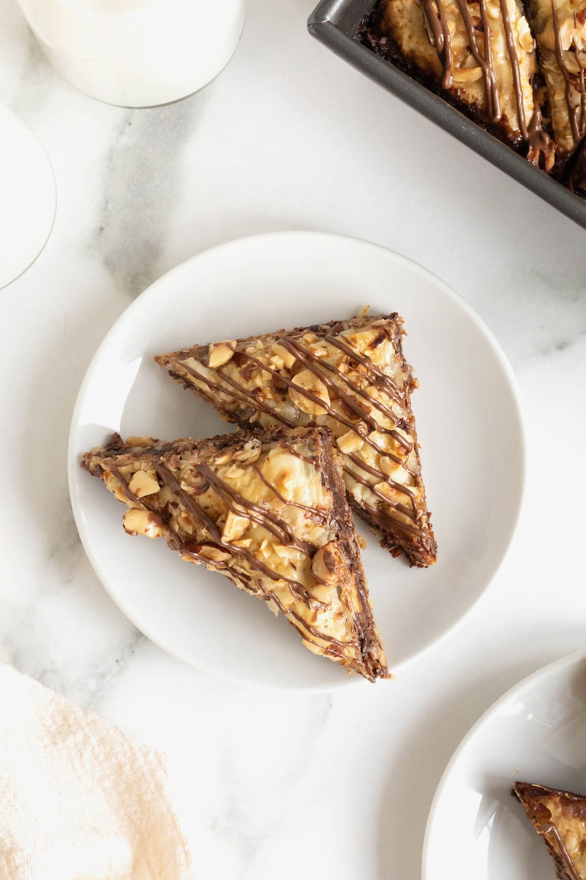 Two pieces of Nutella Baklava on a small white plate on a white marble counter.