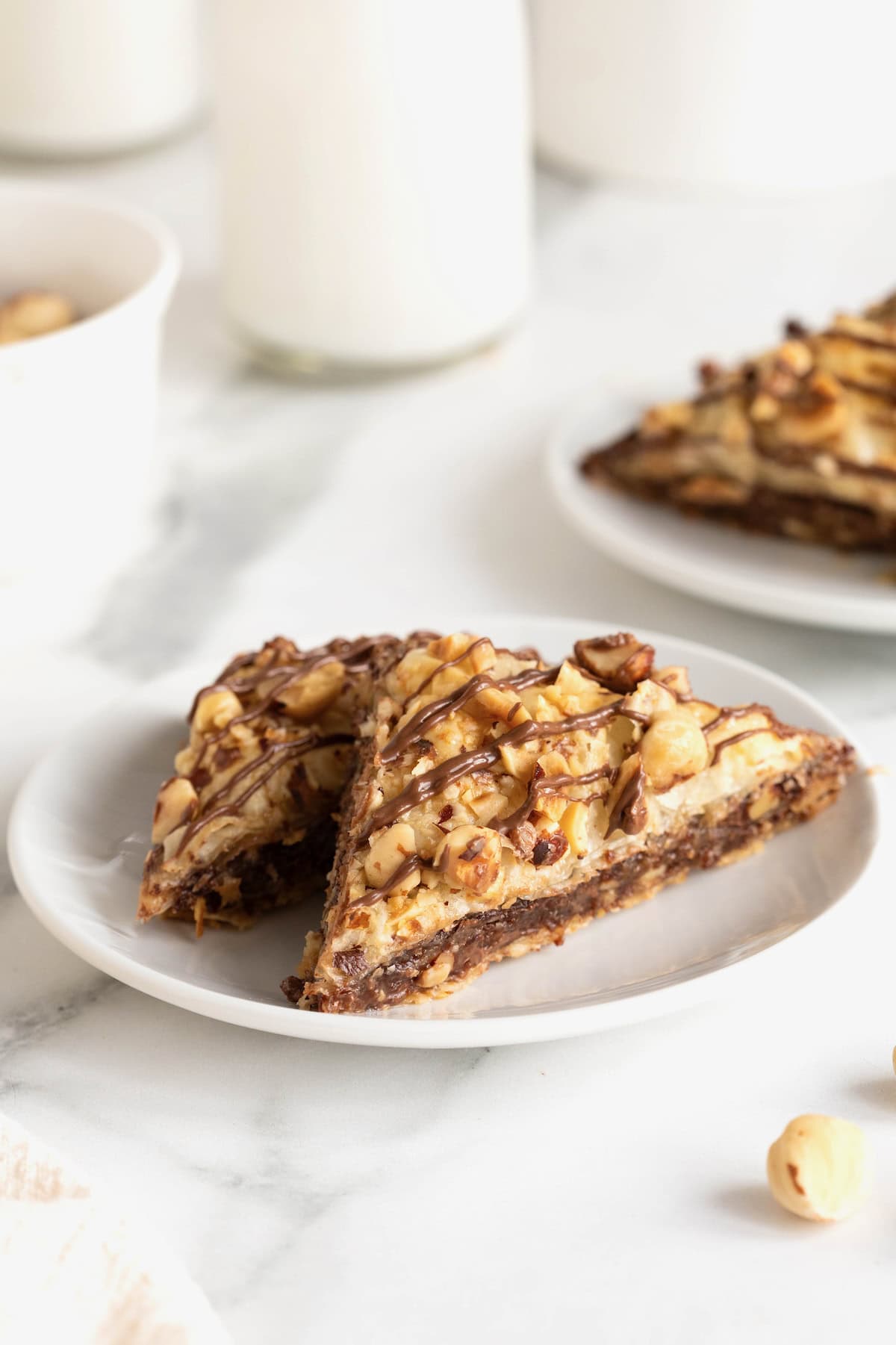 Two pieces of Nutella Baklava on a small white plate on a white marble counter.