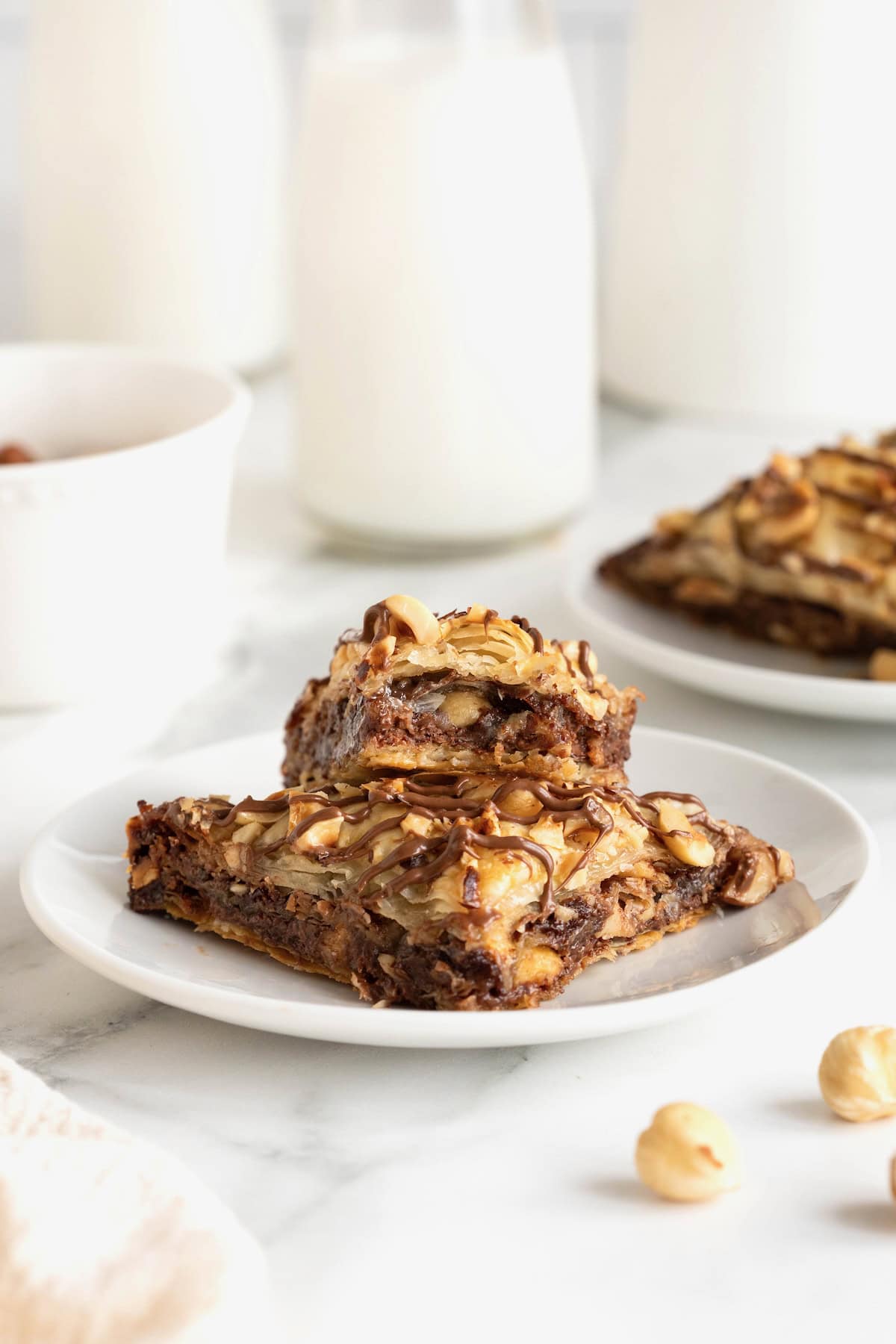 Two pieces of Nutella Baklava stacked on a small white plate. The top piece has a bite out of it.