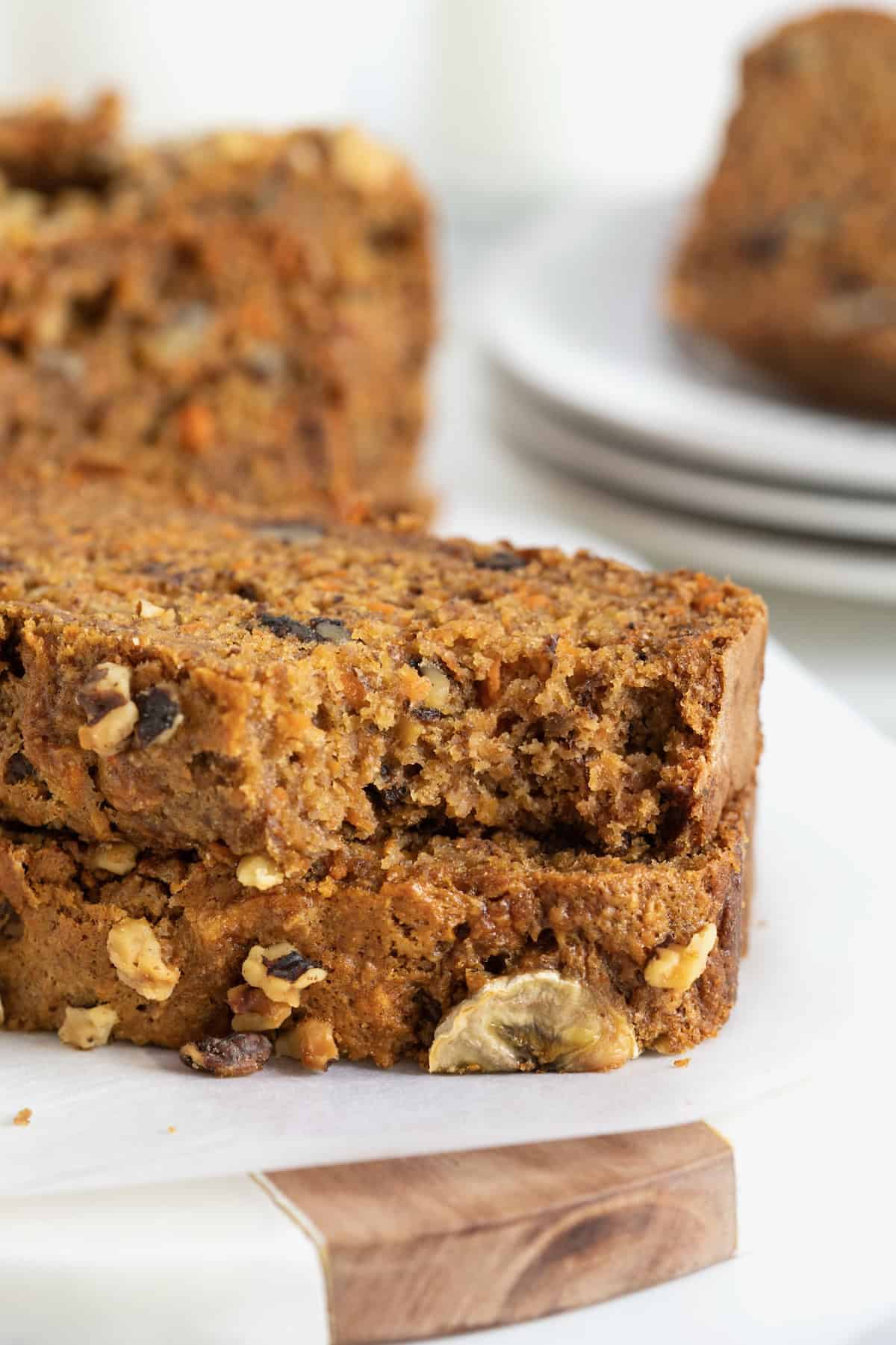 Two pieces of banana nut carrot cake bread stacked on a white cutting board.
