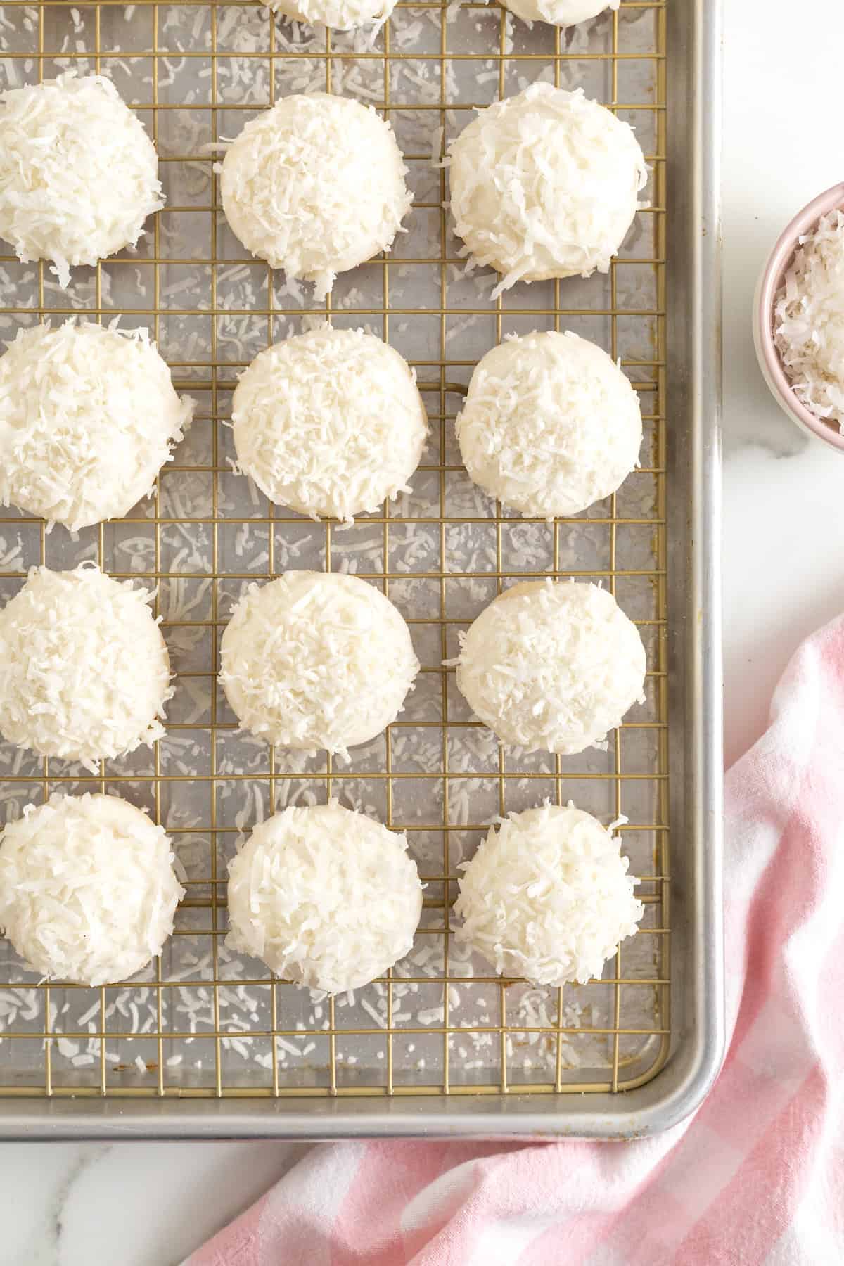 White chocolate dipped coconut cookies on a metal cooling rack.
