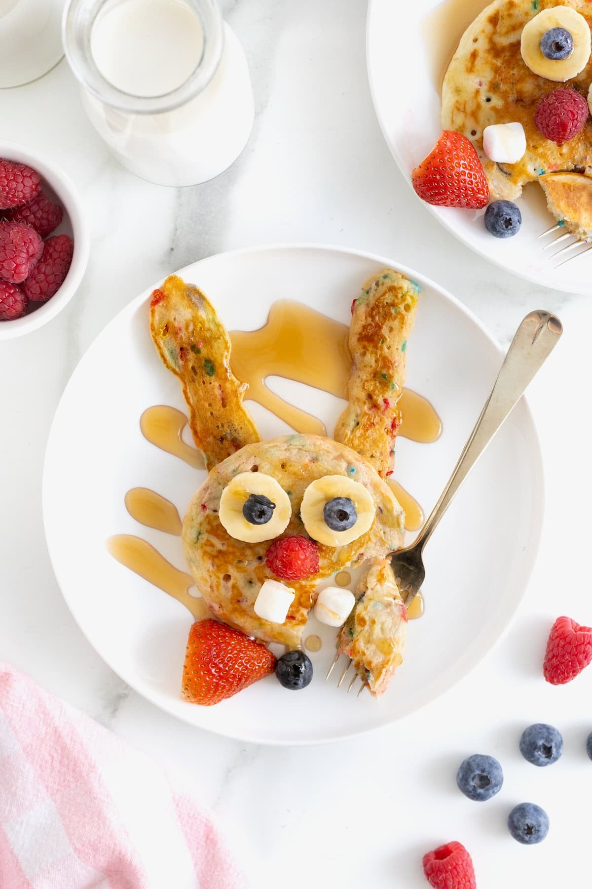 Bunny shaped pancakes on a white plate drizzled with syrup.