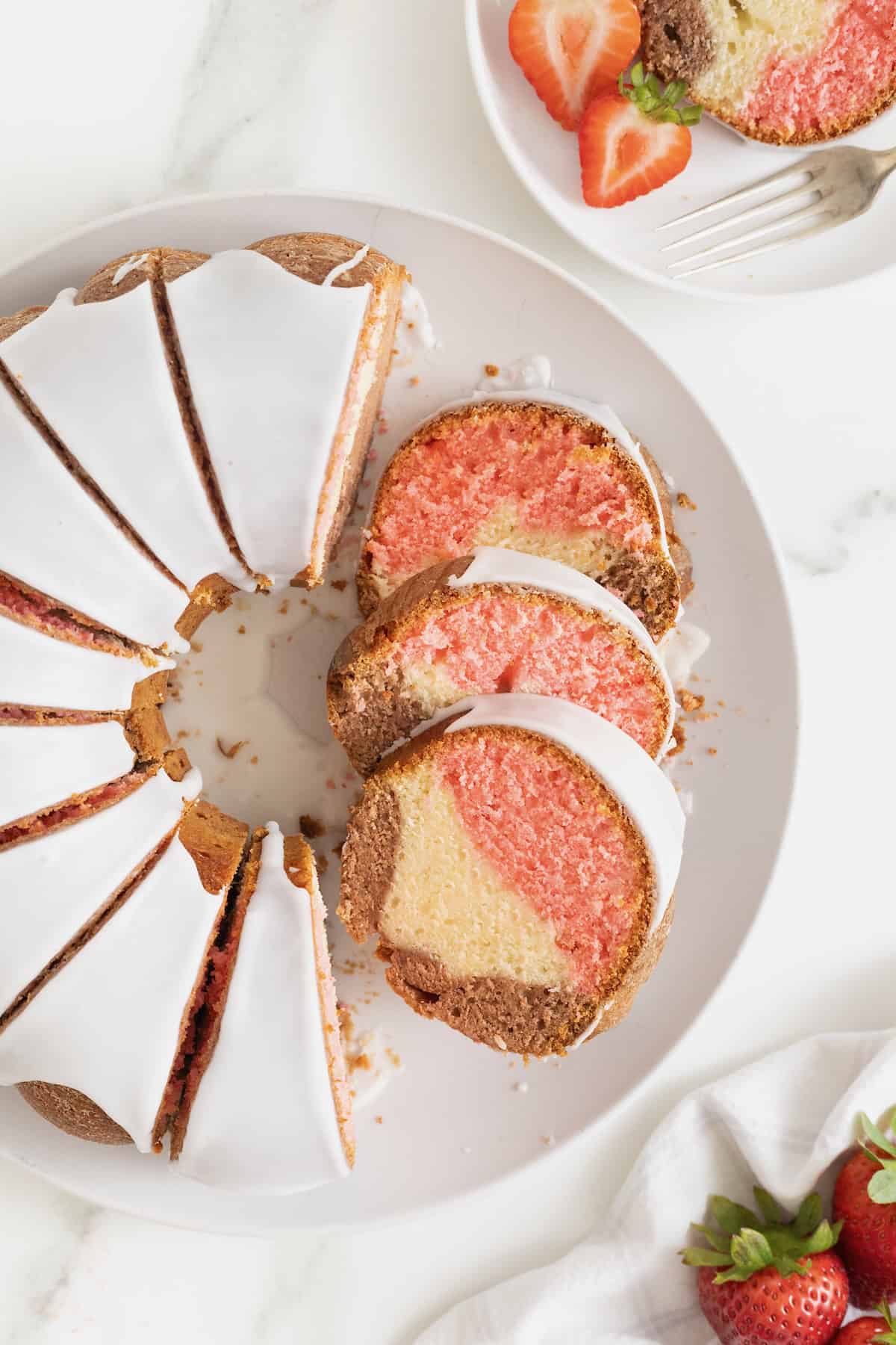 A Neapolitan pound cake cut into slices on a white cake platter.