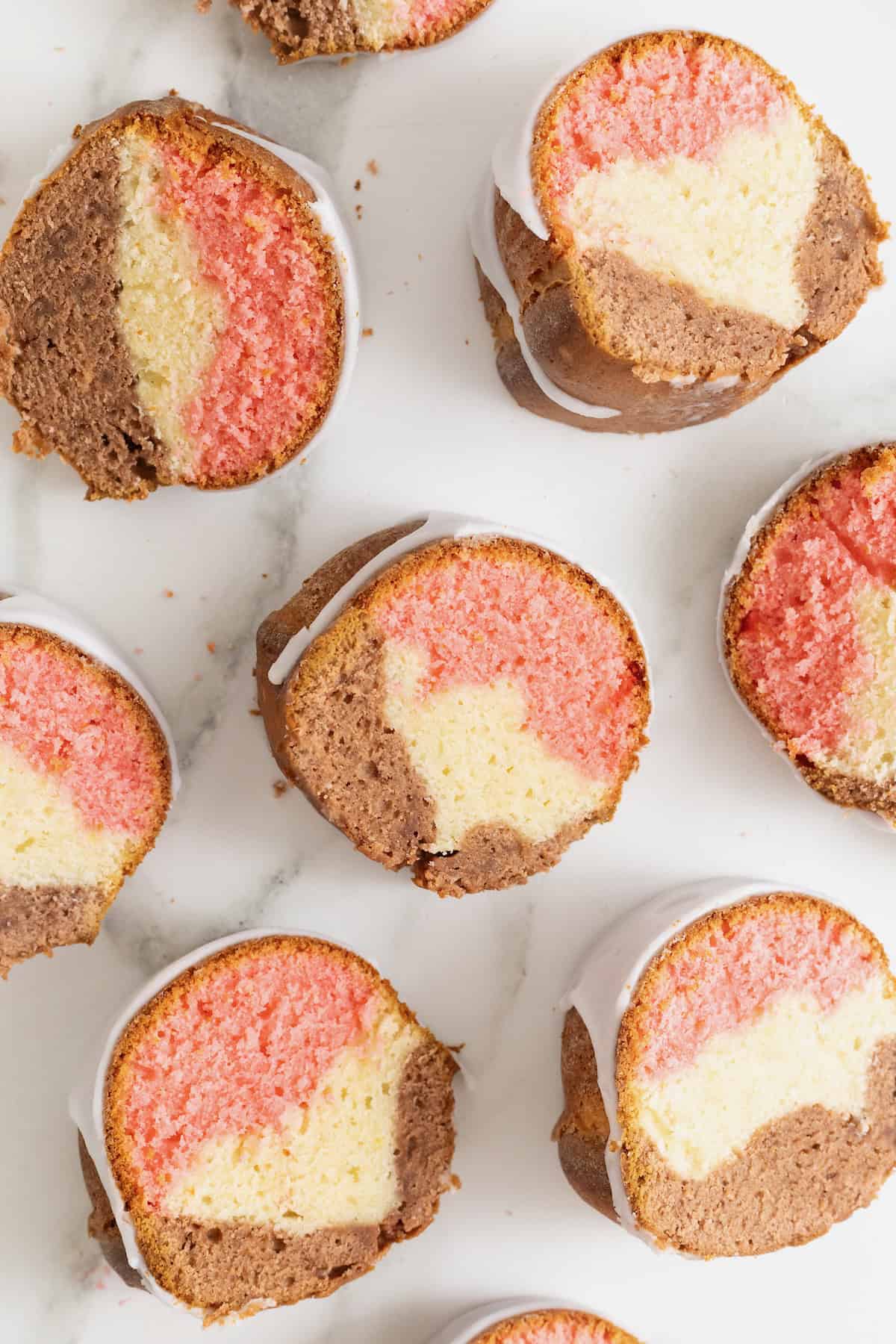Slices of Neapolitan pound cake on a white marble surface.