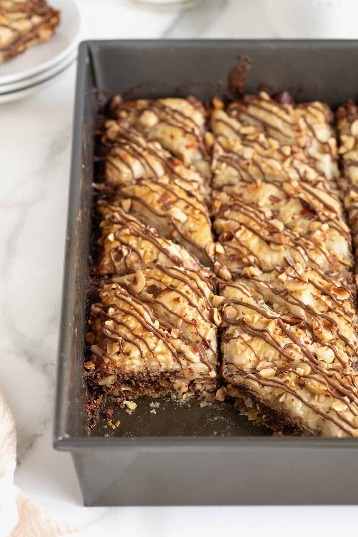 An aluminum baking pan of Nutella Baklava. One piece is missing from the bottom left corner.