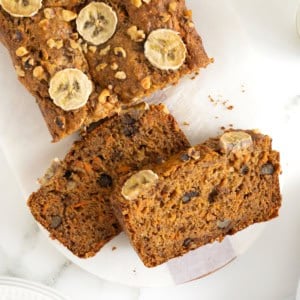 A loaf of whole wheat banana nut carrot cake bread on a white surface.