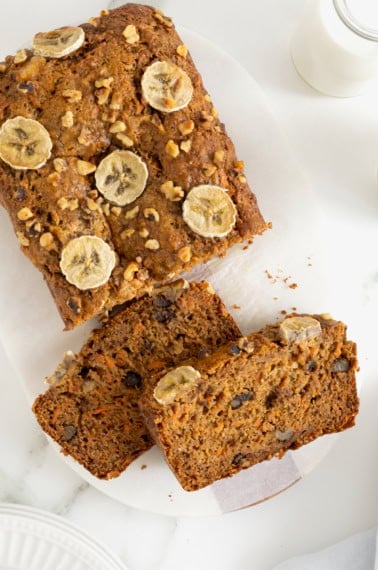 A loaf of whole wheat banana nut carrot cake bread on a white surface.