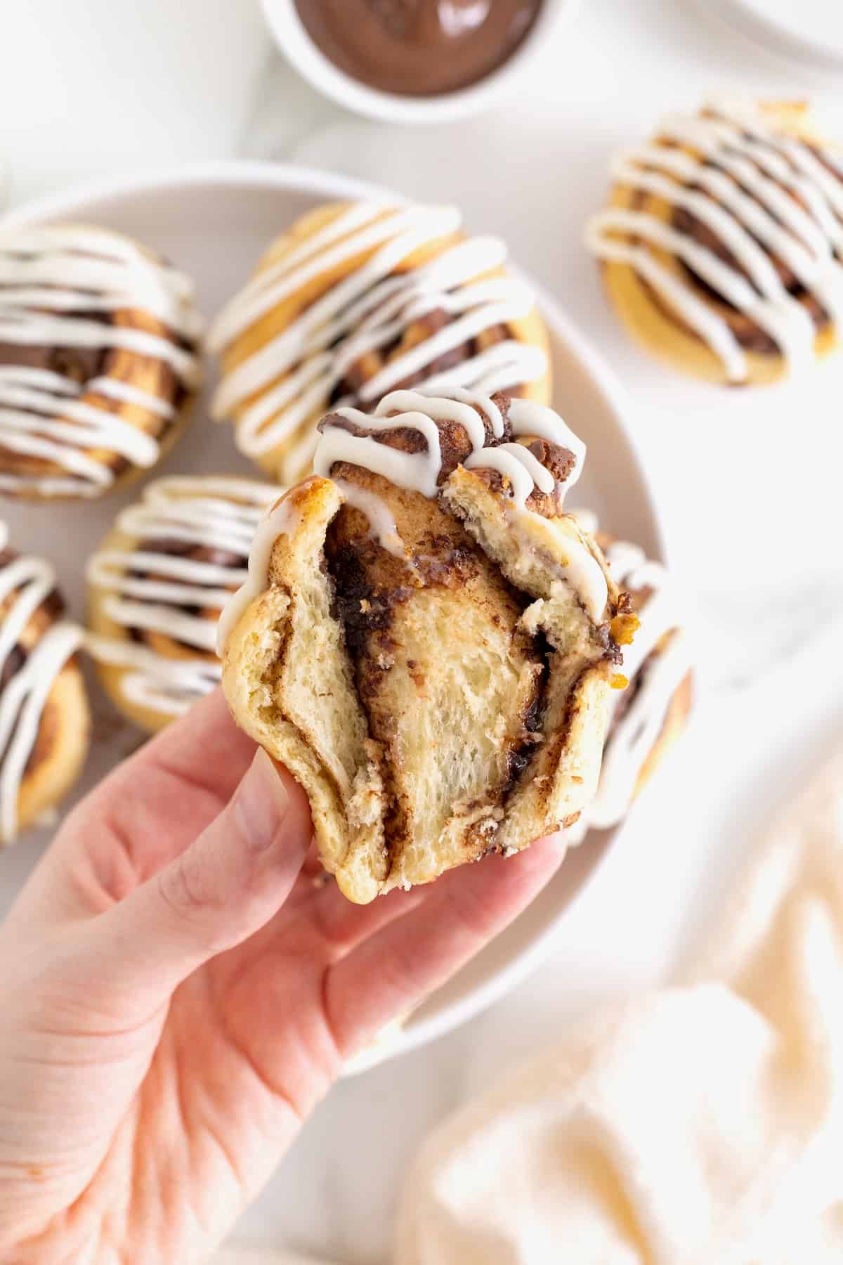 A hand holding a Nutella roll muffin that has been cut in half to show the ribbons of Nutella.