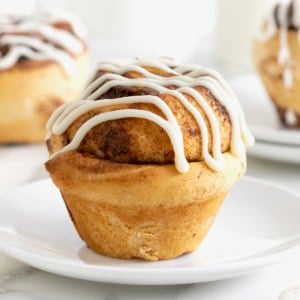 A Nutella roll drizzled with icing on a small white plate.