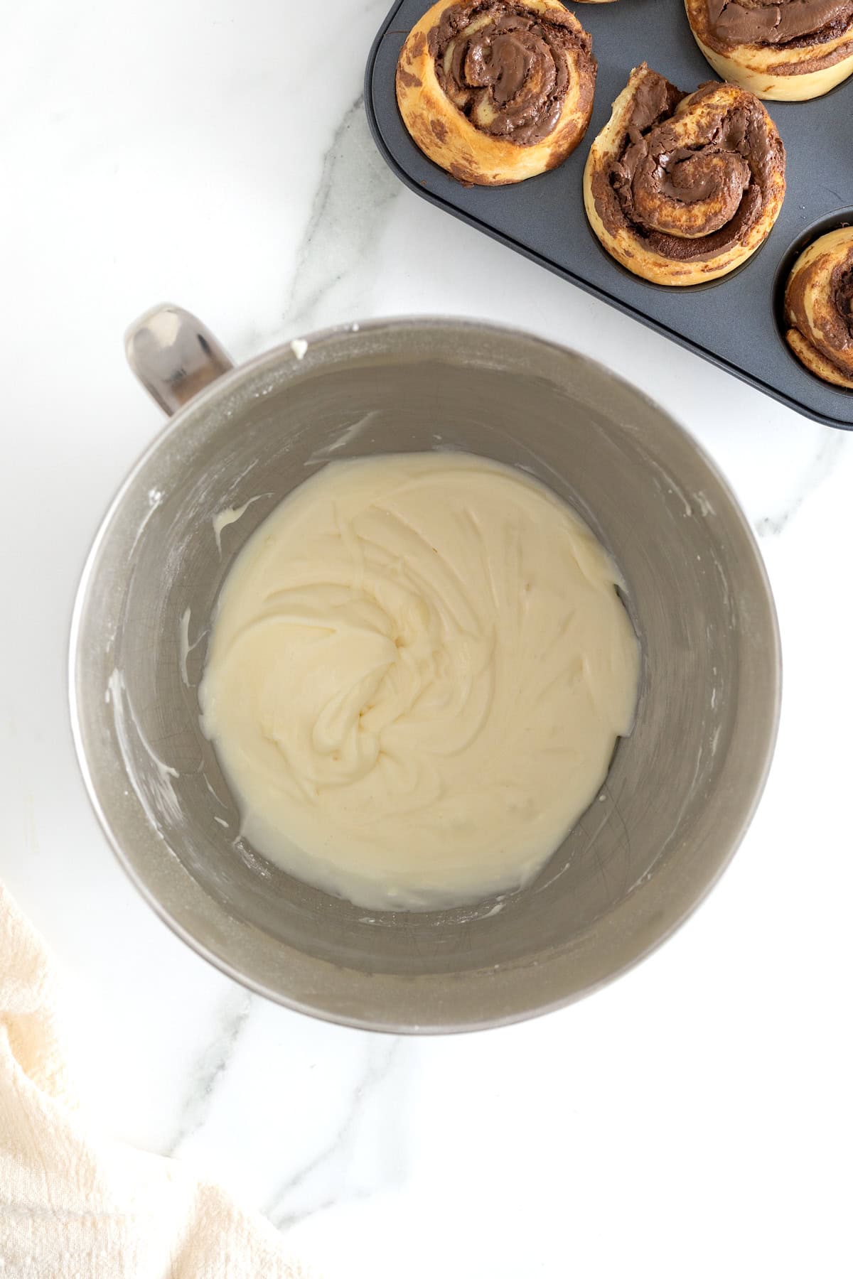 Cream cheese icing in the bowl of an electric mixer.