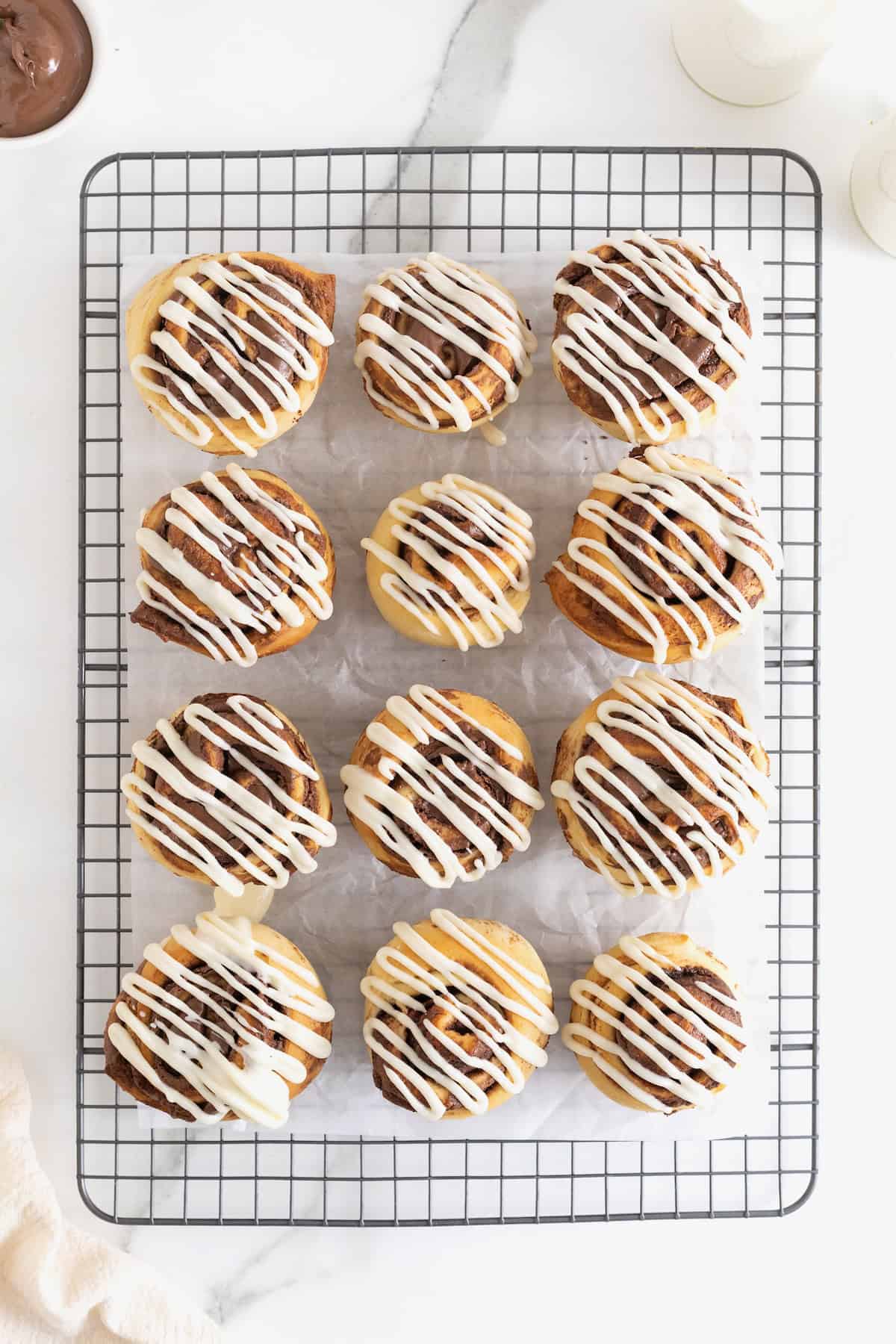 Twelve Nutella roll muffins on a parchment lined wire cooling rack.