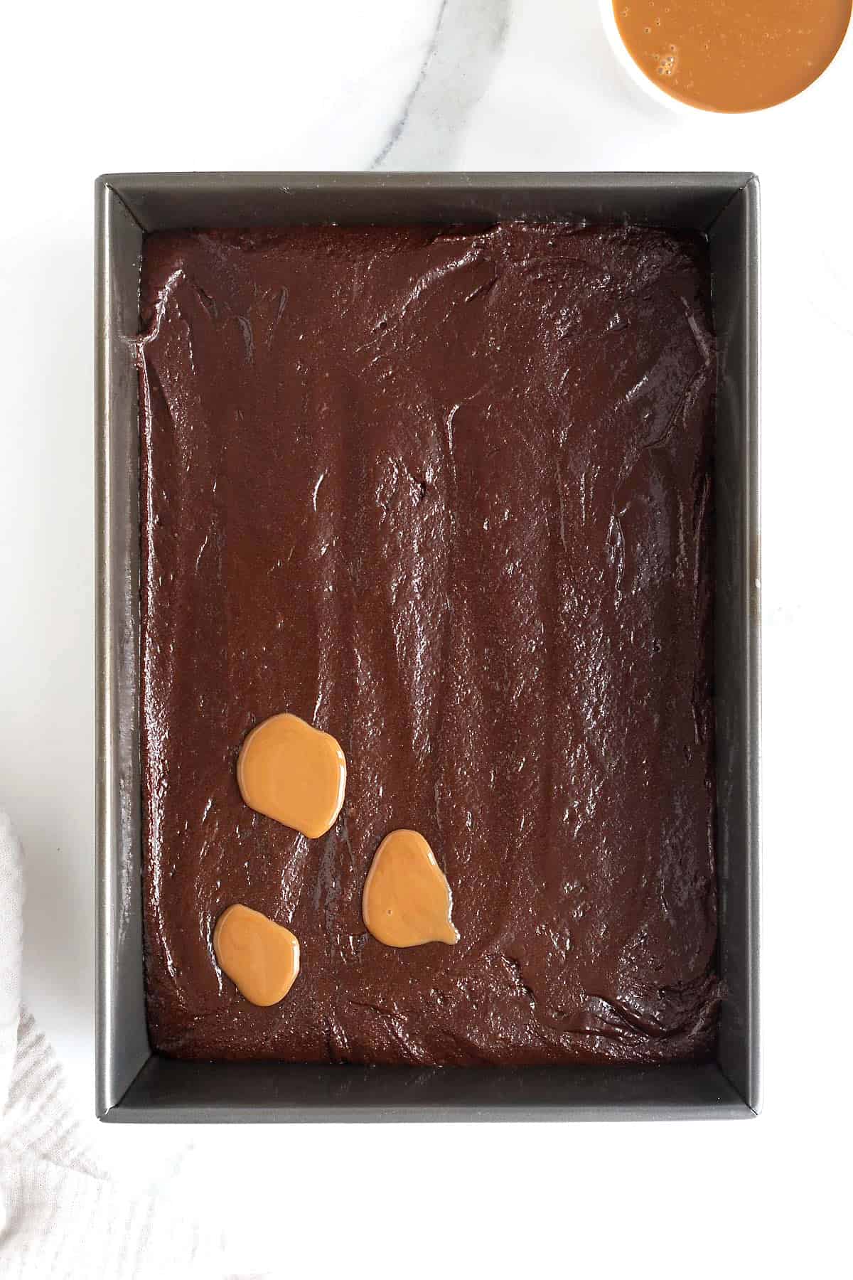 Dollops of caramel on top of brownie batter.