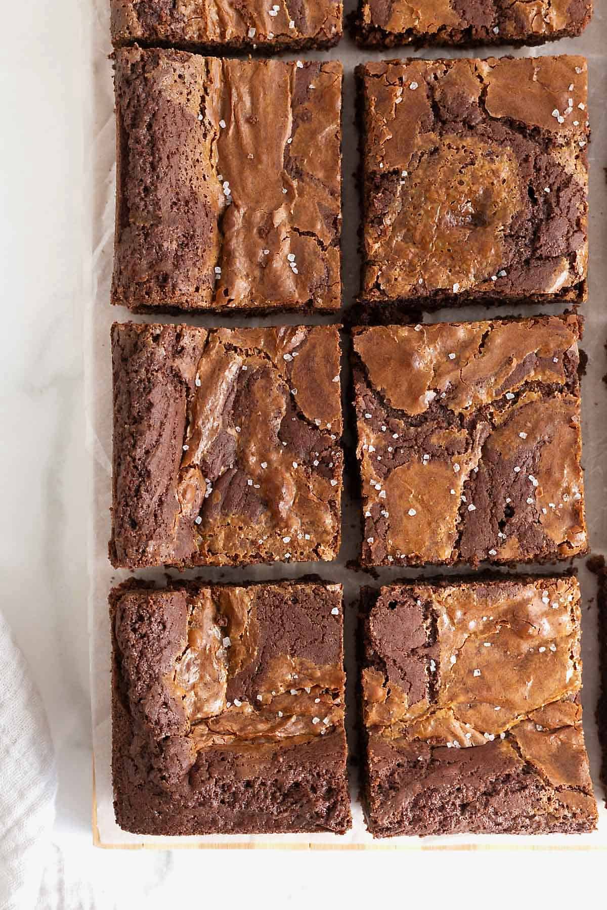 Dulce de leche brownies cut into squares on a parchment lined cutting board.