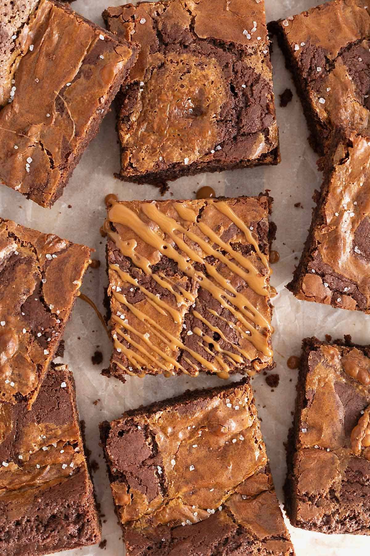 Salted dulce de leche brownies on a parchment lined surface.