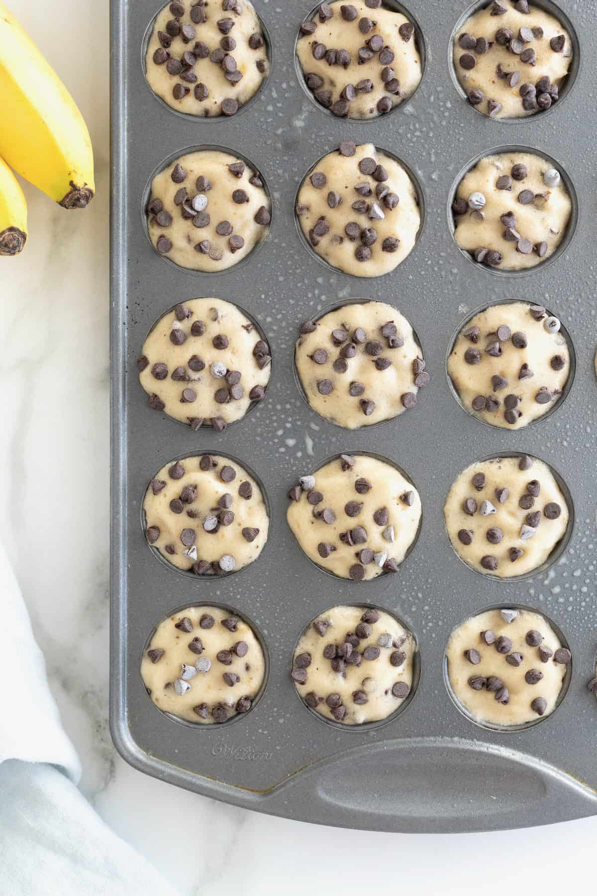 Two-Ingredient Banana Chocolate Chip Ice Cream Bites in an aluminum mini muffin pan on a white marble counter.