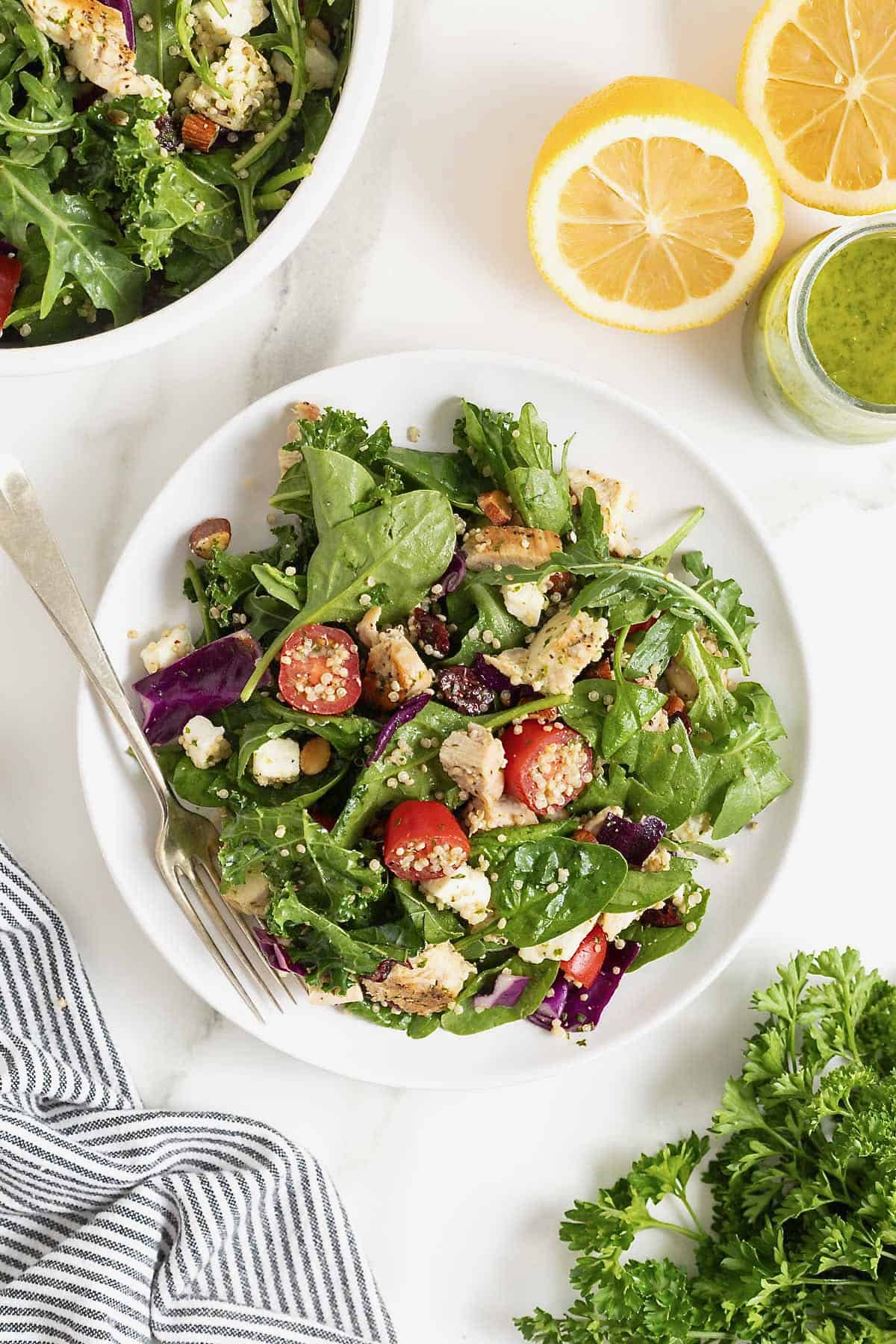A white plate of salad with cherry tomato halves, quinoa and chicken.