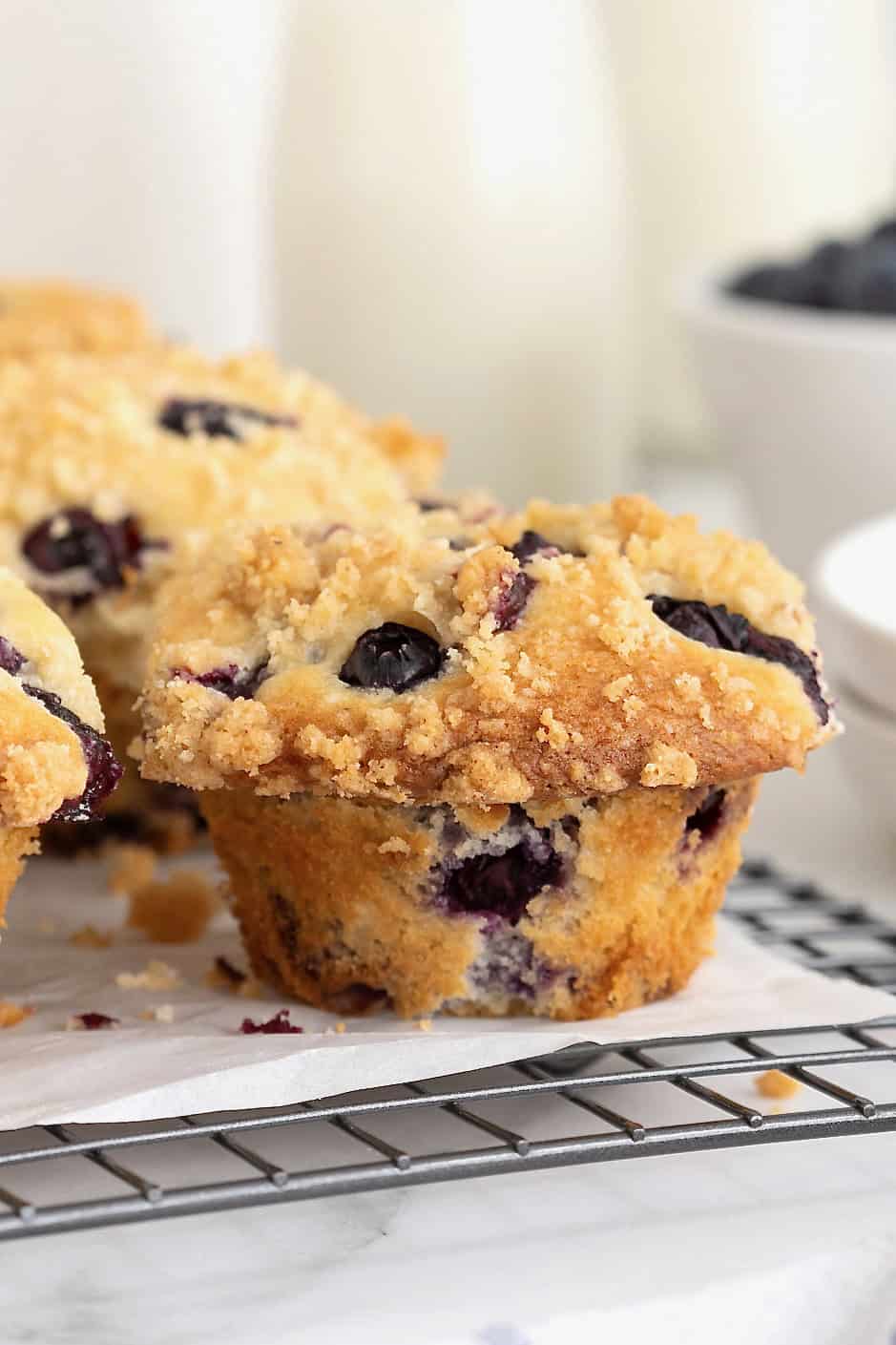 Blueberry streusel muffins on a parchment lined cooling rack.