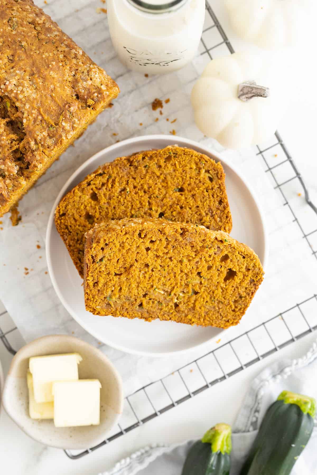 Two slices of whole wheat pumpkin zucchini bread on a small white rimmed plate.