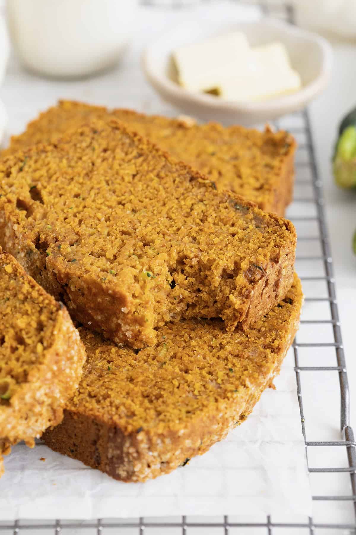 Several slices of whole wheat pumpkin zucchini bread on a wire cooling rack.