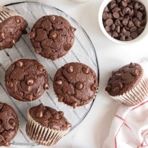 A round wire cooling rack scattered with chocolate muffins.