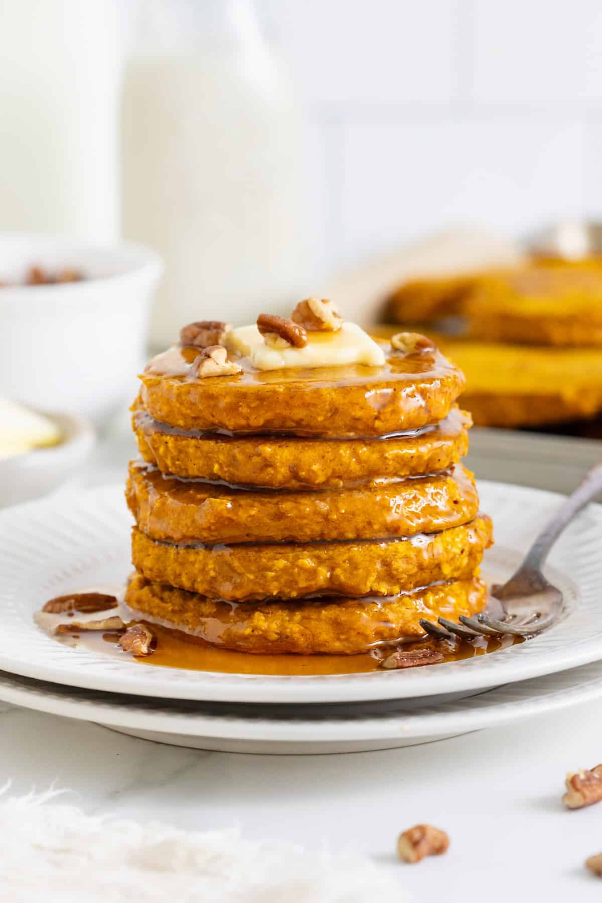 A stack of five pumpkin oatmeal pancakes on a white plate. 
