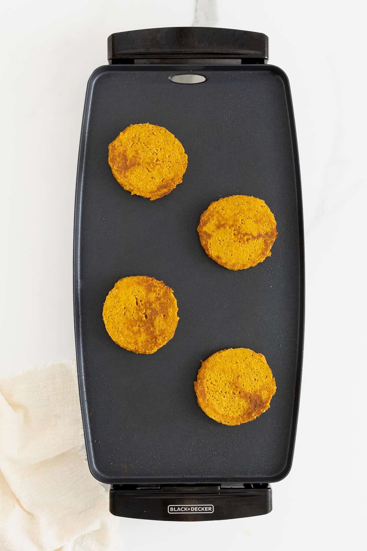 Pumpkin oatmeal pancakes on a dark griddle.