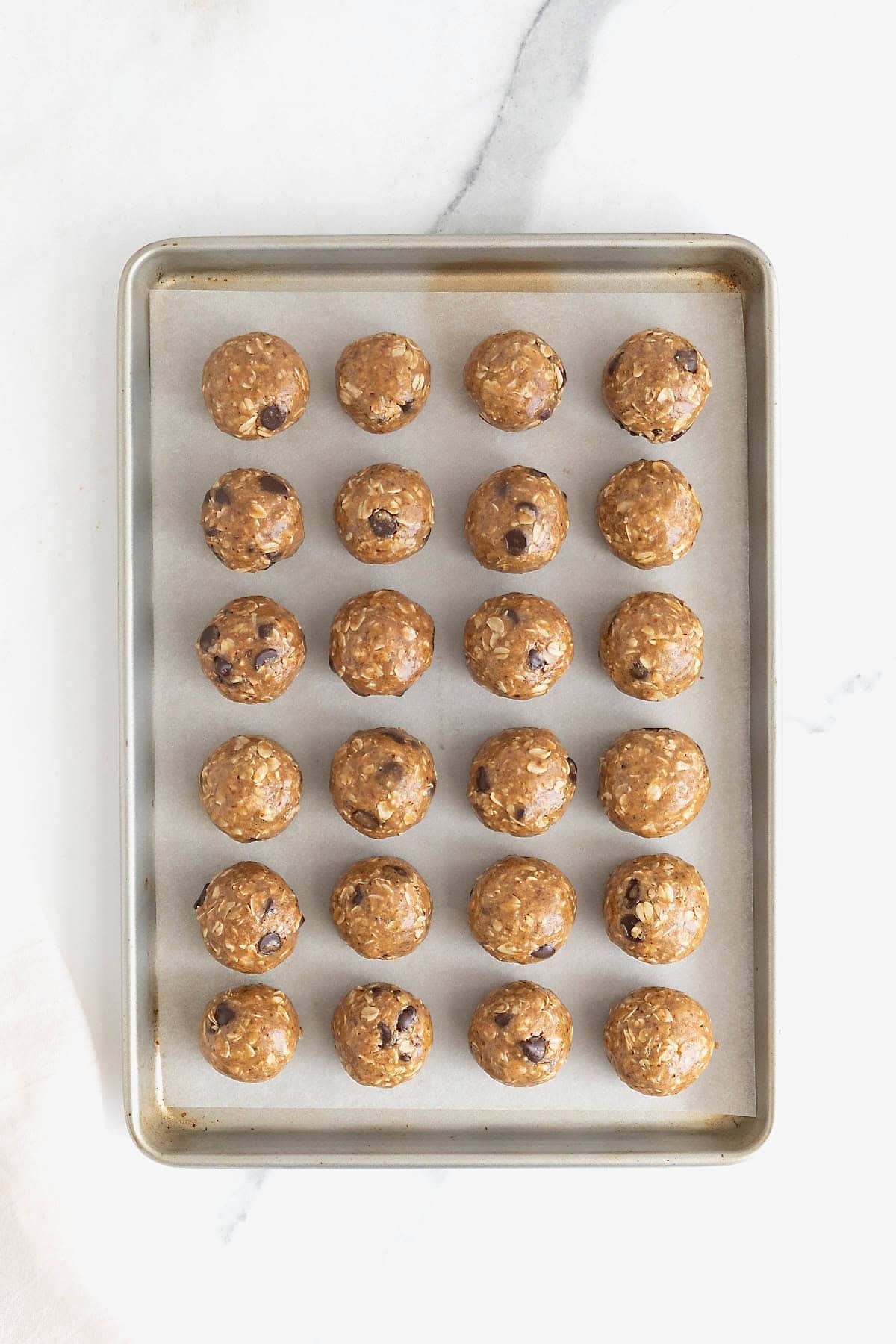 24 lactation bites on a parchment lined baking sheet.