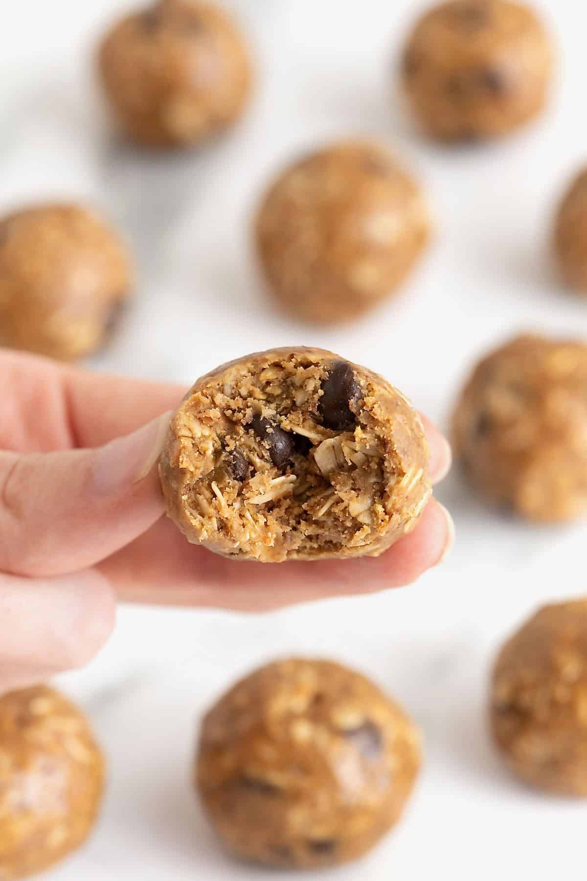 A hand holding a snack ball with a bite taken out of it.