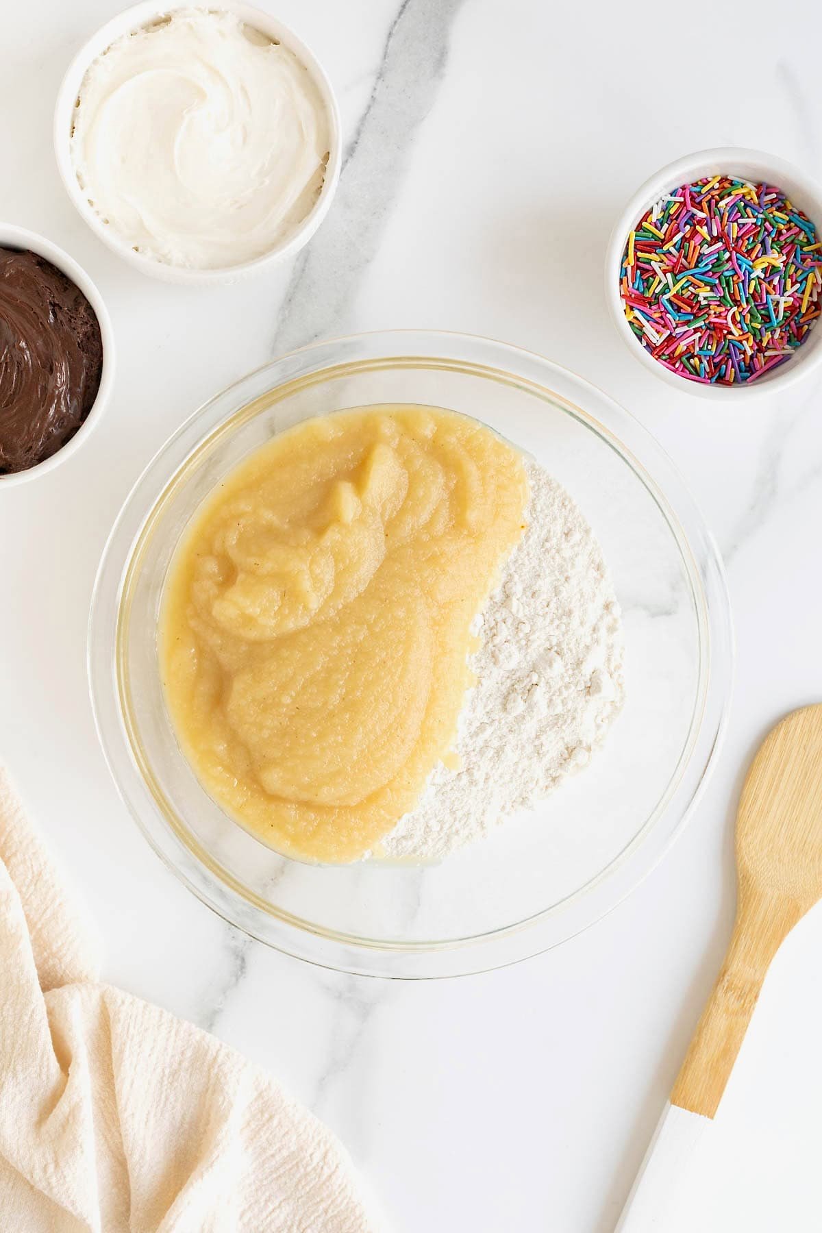 Applesauce and dry vanilla cake mix in a large glass mixing bowl.