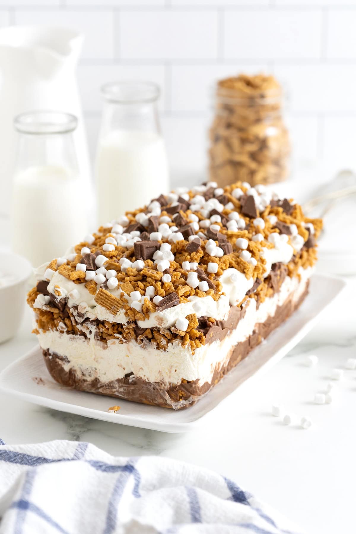 A layered s'mores ice cream cake topped with marshmallow bits, chocolate chunks and Golden Grahams crumbs.
