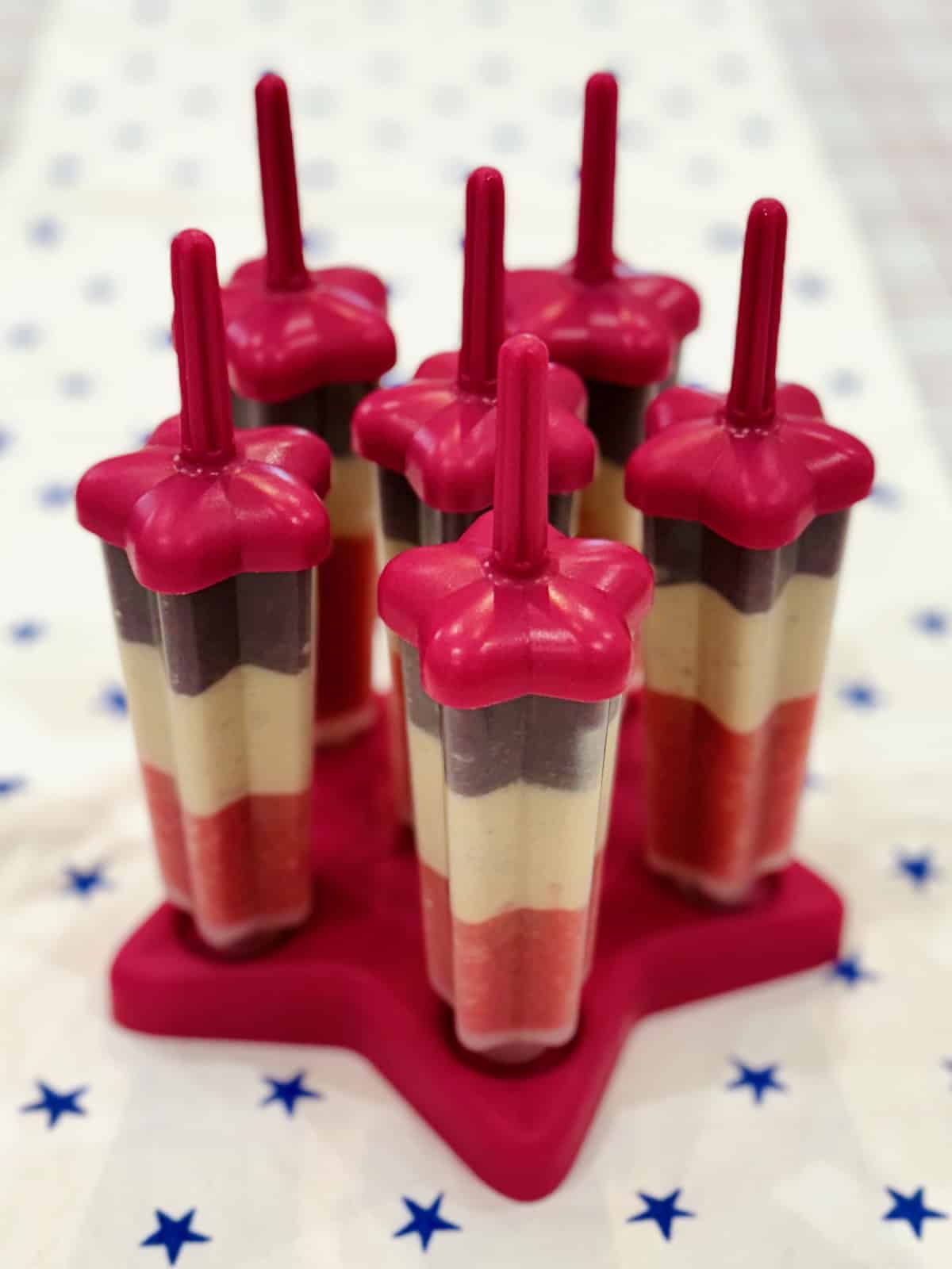 Five start shaped patriotic fruit pops on a star shaped red platter.