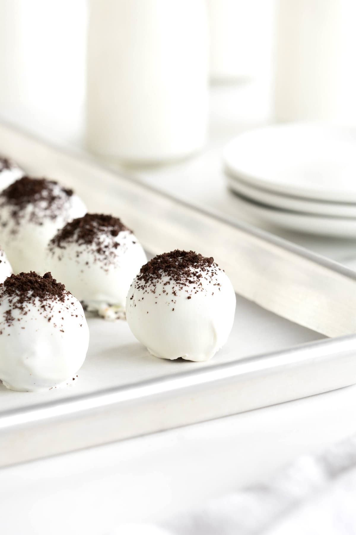 Oreo cake balls on an aluminum baking sheet lined with parchment paper.
