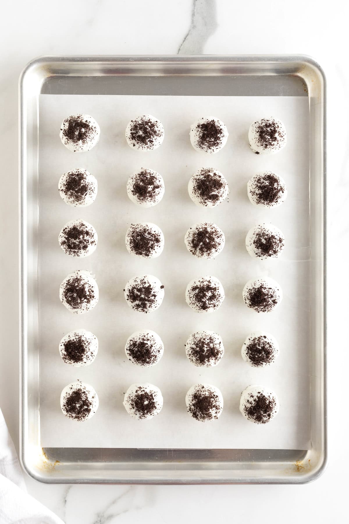 Oreo cake balls on an aluminum baking sheet lined with parchment paper.