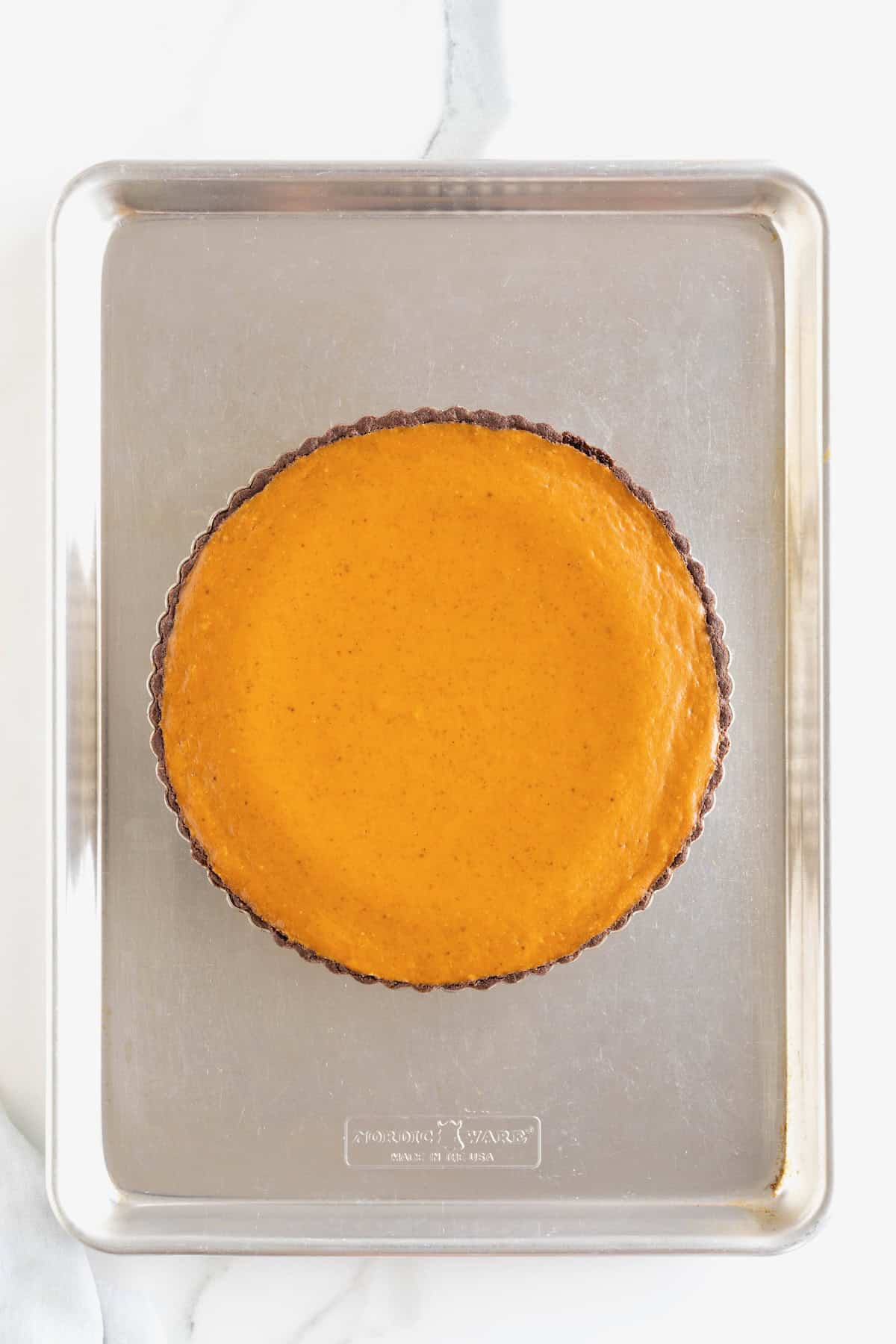 A cooked pumpkin tart on an aluminum baking sheet.