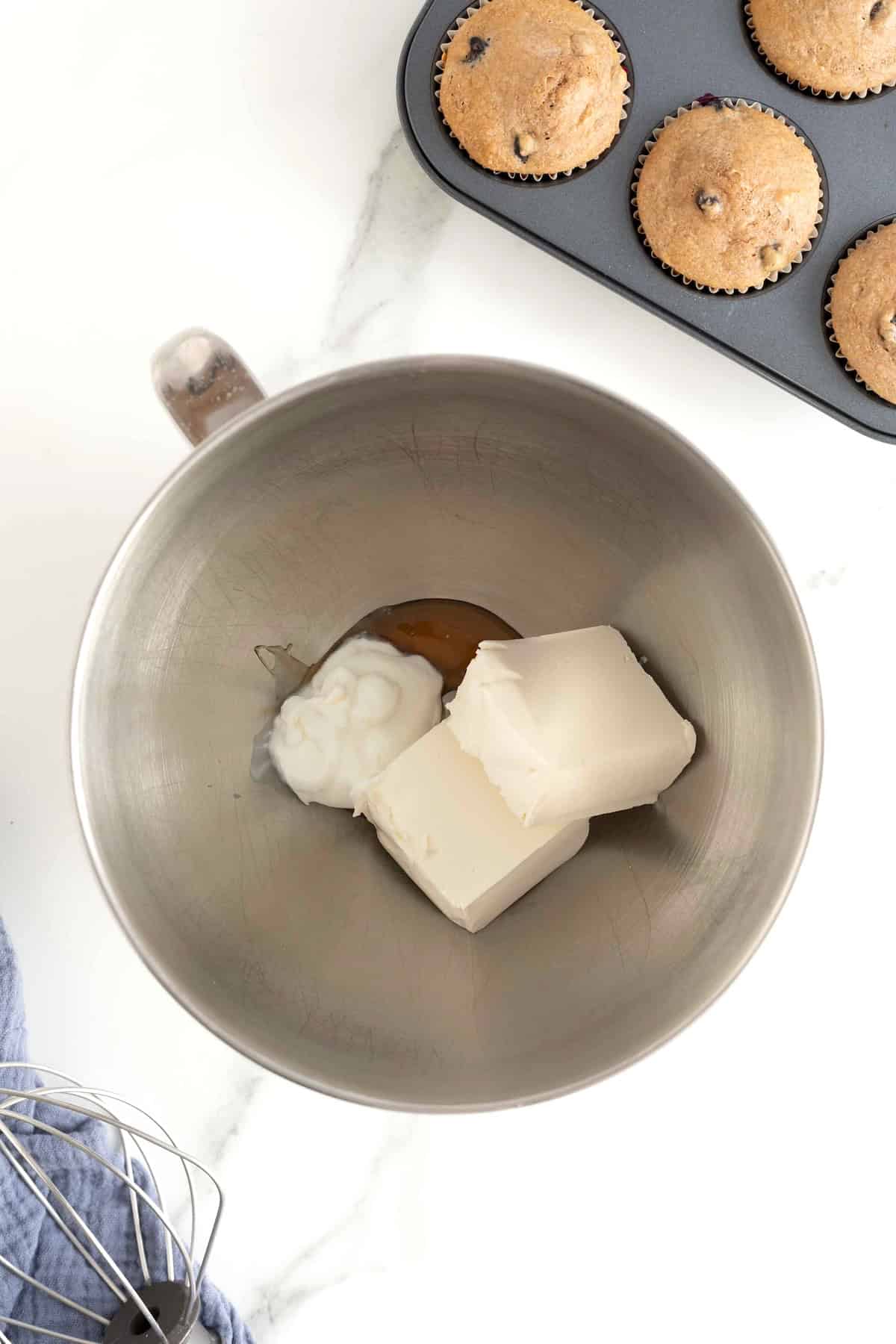Cream cheese, sour cream and maple syrup in a stainless steel bowl.