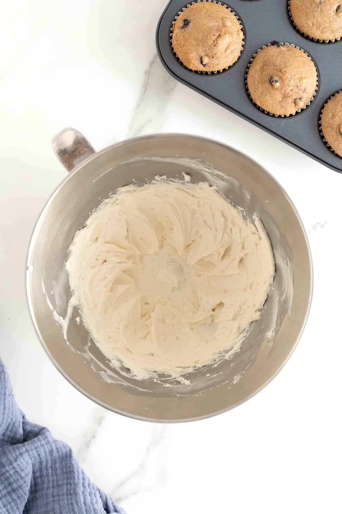 A stainless steel bowl of white frosting.