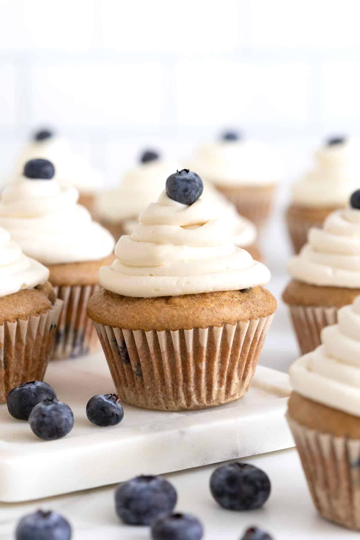 Whole wheat blueberry cupcakes with white icing and a single blueberry garnish.