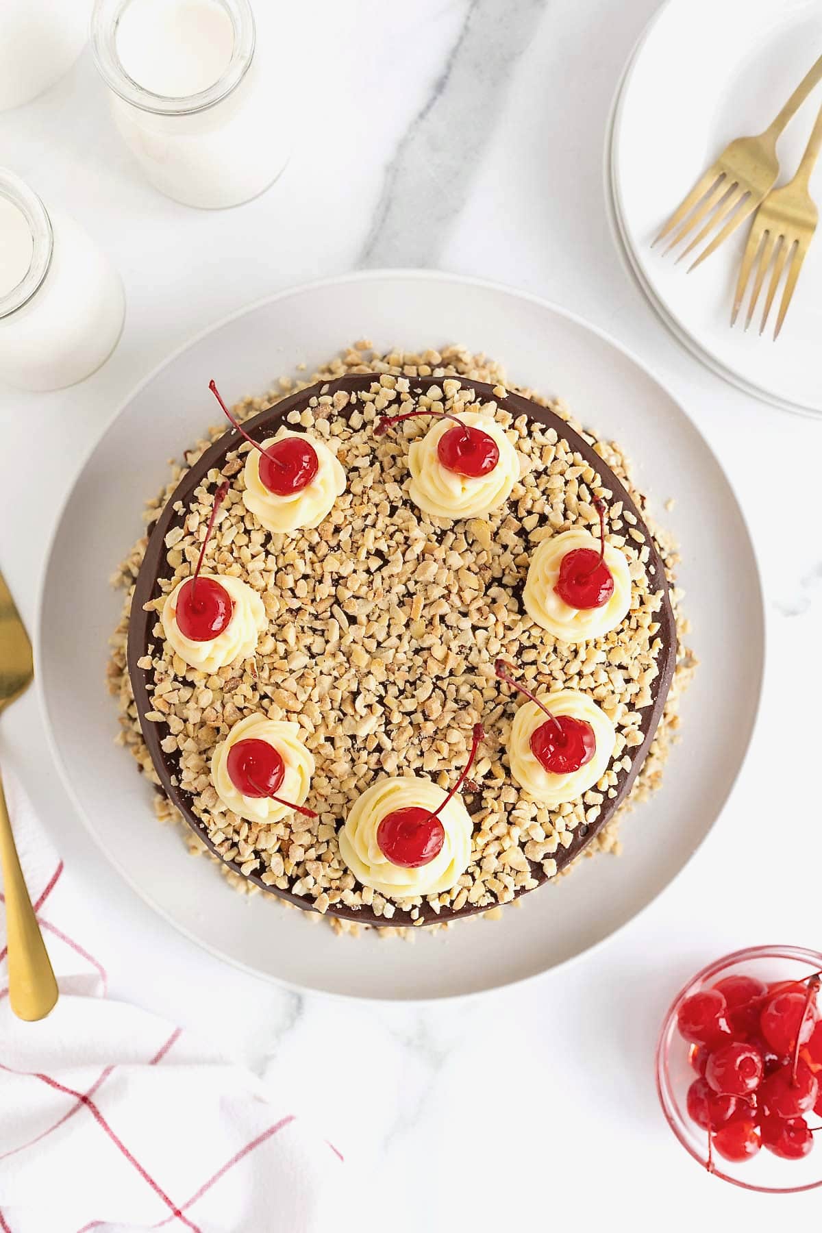 Hot fudge sundae cake topped with maraschino cherries and chopped nuts.