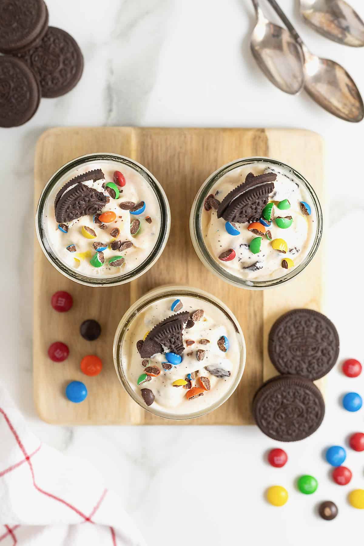 Three homemade blizzards in mason jars on a square light wood cutting board.