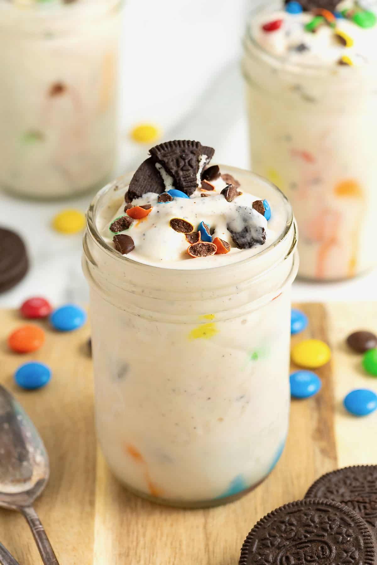 A homemade M&M Blizzard garnished with a piece of Oreo in a wide mouth jar.