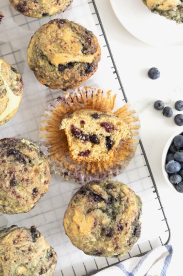 Six blueberry swirl muffins on a wire cooling rack.