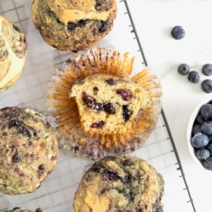 Six blueberry swirl muffins on a wire cooling rack.